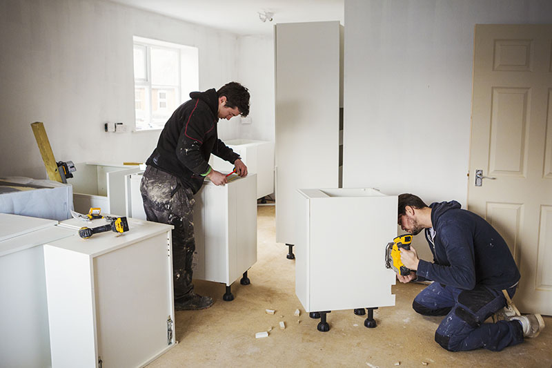 Cabinet installers working on kitchen cabinet placement.